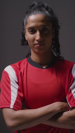 Vertical-Video-Studio-Portrait-Of-Female-Footballer-Wearing-Club-Kit-Against-Grey-Background